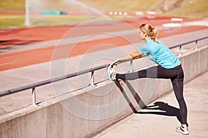 Fitness, legs and woman stretching in stadium for race, marathon or competition training for health. Sports, runner and