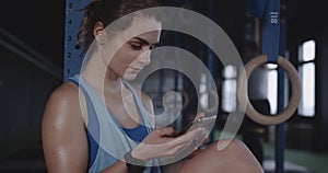 Fitness lifestyle app. Beautiful athlete woman using smart phone to track physical activity after workout at modern gym.