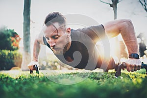 Fitness lifestyle concept.Muscular athlete exercising push up outside in sunny park. Fit shirtless male fitness model in