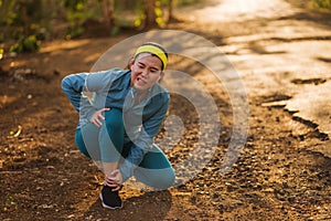 Fitness lifestyle portrait of young attractive Asian runner woman suffering sport injury during jogging workout on sunset road