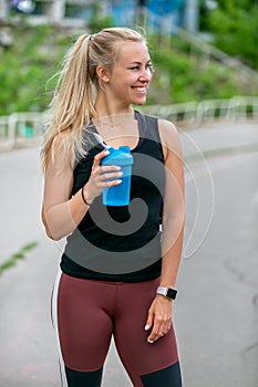 Fitness lifestyle. Sports young woman drinks water from a bottle during a training. Workout at the stadium. Healthy life concept