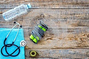 Fitness for loosing weight. Jump rope, measure tape and water on wooden background top view copyspace