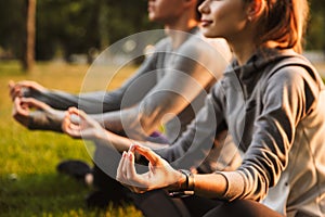 Fitness loving couple friends in park make meditate exercises.