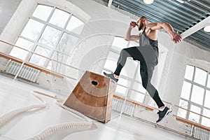 Strong man doing a box jump exercise at light hall