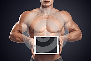 Fitness male holding horizontally digital tablet with blank scre