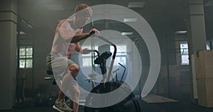 Fitness man on bicycle doing spinning at gym. Fit young male working out on gym bike. Male exercising on bicycle in