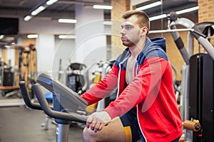 Fitness man on bicycle doing spinning at gym. Fit young man working out on gym bike.