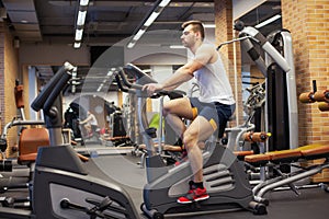 Fitness man on bicycle doing spinning at gym. Fit young man working out on gym bike.