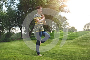 Fitness man doing exercise on one leg  in the park. enjoying nature, yoga and meditation concept. spiritual practices.zen