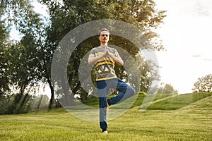 Fitness man doing exercise on one leg  in the park. enjoying nature, yoga and meditation concept. spiritual practices.zen