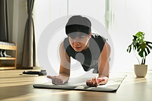 Fitness man doing plank exercise on mat during morning training.