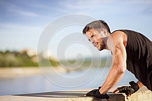 Fitness man doing push-ups on wall by river