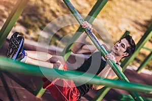 Fitness man doing workouts on horizontal bar outdoors