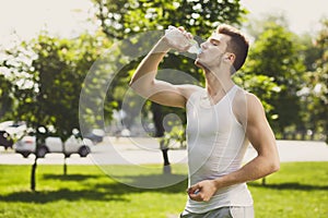 Fitness man drinking water in park otdoors