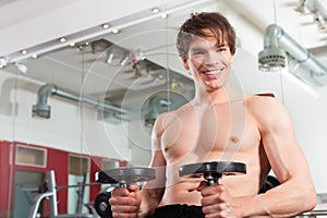 Fitness - man exercising with barbell in gym