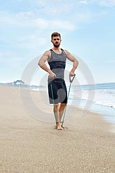 Fitness Man Exercising At Beach, Doing Expander Exercise Outdoor