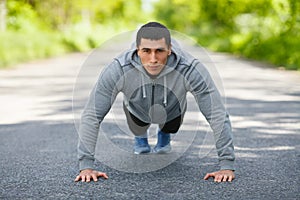 Fitness man exercising push ups, outdoor. Muscular male cross-training on city park