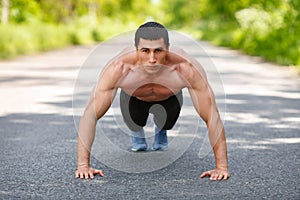 Fitness man exercising push ups, outdoor. Muscular male cross-training on city park