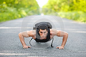 Fitness man exercising push ups, outdoor. Muscular male cross-training on city park