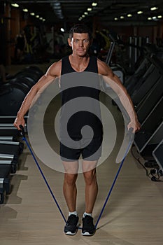 Fitness man exercising with stretching band in the gym. Muscular sports man exercising with elastic rubber band.