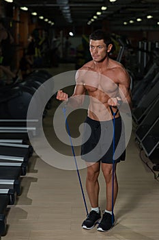 Fitness man exercising with stretching band in the gym. Muscular sports man exercising with elastic rubber band. Guy working out w