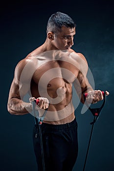 Fitness man exercising with stretching band. Muscular sports man exercising with elastic rubber band. Guy working out