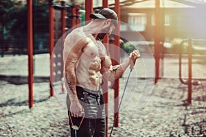 Fitness man exercising with stretching band in outdoor gym.