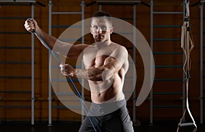 Fitness man exercising with stretching elastic rubber band in the gym