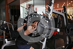 Fitness man in the gym doing squat . Man with dumbbell weight training equipment gym. Indoor, instructor.