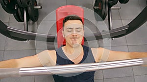 Fitness man in gym training chest muscles doing flat bench press with barbell.