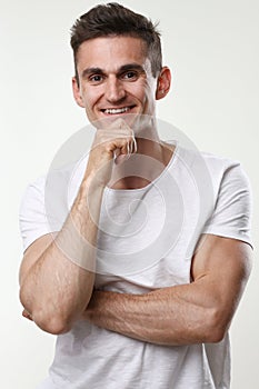 Fitness man portrait cute in a white tank top on a gray background