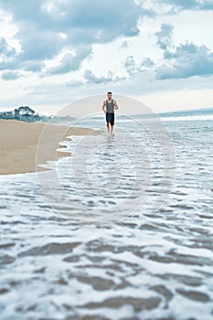 Fitness Man Running On Beach. Runner Jogging During Outdoor Workout