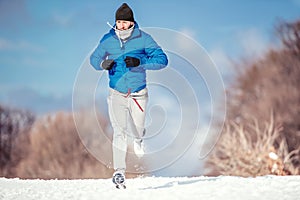 Fitness man running outdoor in snow on a cold winter day