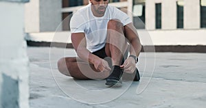 Fitness, man and shoes in sports preparation, exercise or workout for roof top training in the city. Athletic male tying