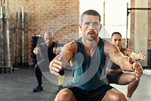 Fitness man squatting with class at gym
