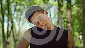 Fitness man warm up neck outdoor. Closeup of fit man stretching in park