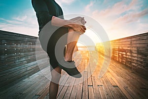 Fitness man warming up and stretching legs before workout outdoors at sunset or sunrise. Sport and healthy lifestyle