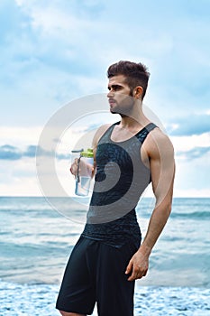 Fitness Man With Water Bottle Resting After Workout At Beach