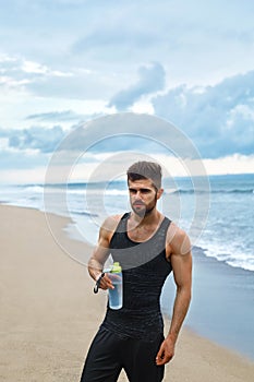 Fitness Man With Water Bottle Resting After Workout At Beach