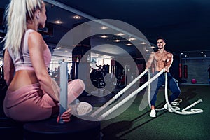 Fitness man working out with battle ropes at gym