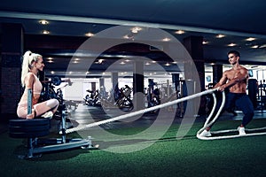 Fitness man working out with battle ropes at gym