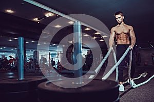 Fitness man working out with battle ropes at gym