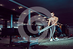 Fitness man working out with battle ropes at gym