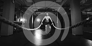Fitness man working out with battle ropes at a gym