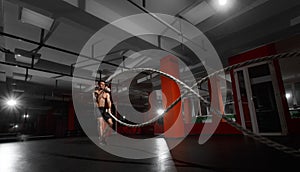 Fitness man working out with battle ropes at a gym