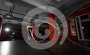 Fitness man working out with battle ropes at a gym