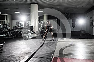 Fitness man working out with battle ropes at gym. Battle ropes fitness man at gym workout exercise fitted body. Fitness man traini