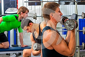 Fitness men friends in gym workout weights with equipment.