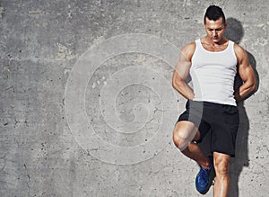 Fitness model man standing against grey background