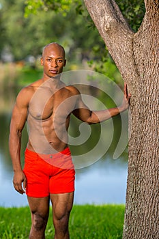 Fitness model posing in bright red shorts at a park setting